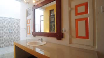 Une salle de bain avec un grand miroir, un lavabo et un mur recouvert de carreaux.