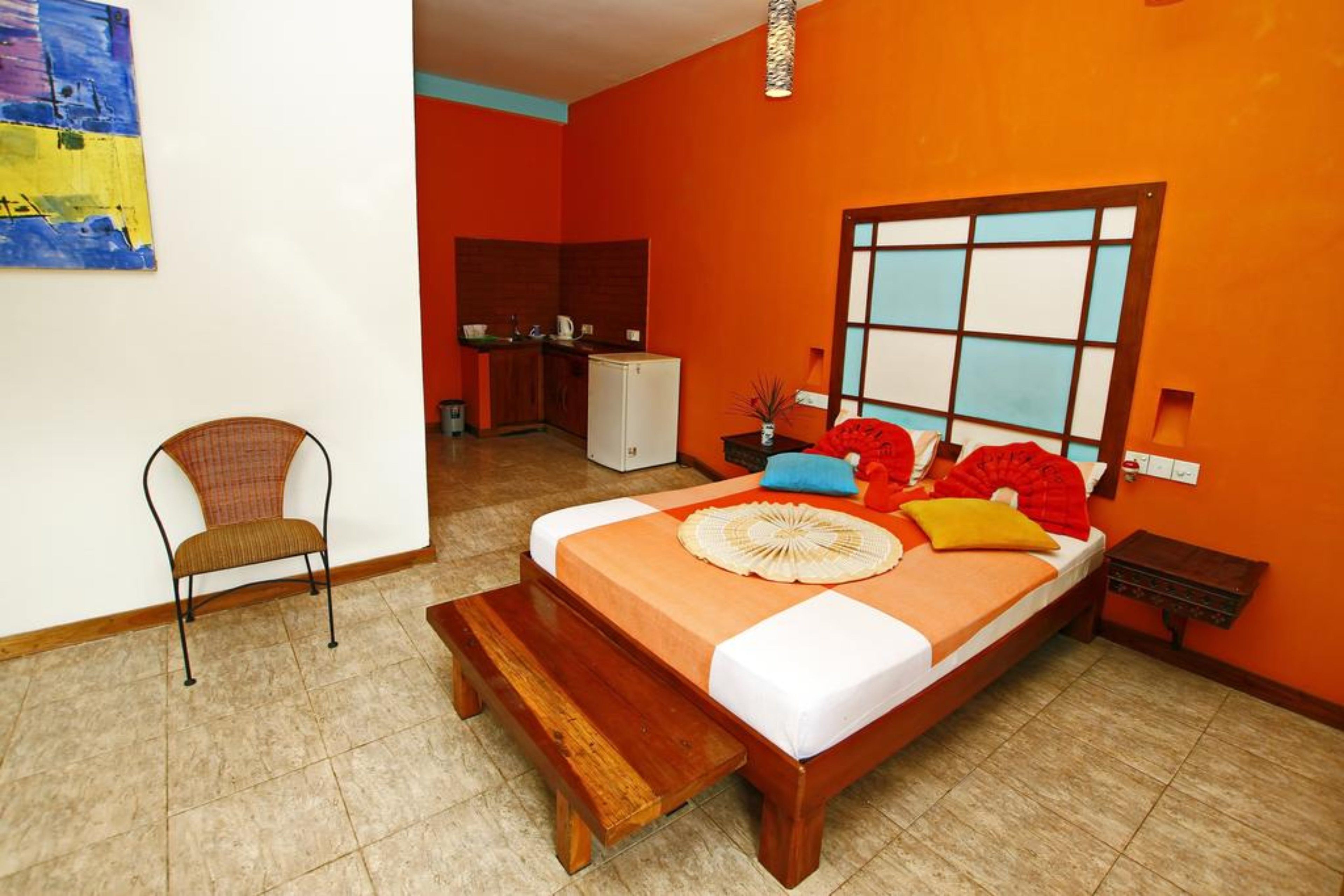 A room with a bed, a chair, a small kitchenette, and a window with a view.