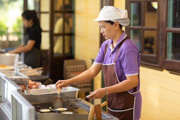 A person cooking at a counter with various cooking utensils and ingredients. - Khaoyai Fantasy Resort (Pak Chong)