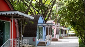 Une rangée de petits bâtiments colorés, avec des marches menant à l’entrée, le tout entouré d’arbres.