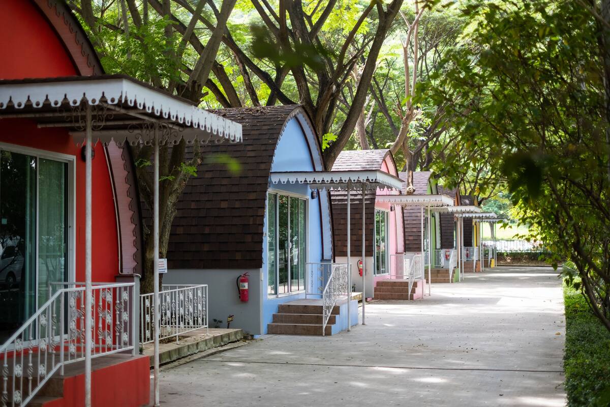 Una hilera de edificios pequeños y coloridos con escalones que conducen a la entrada, rodeados de árboles.