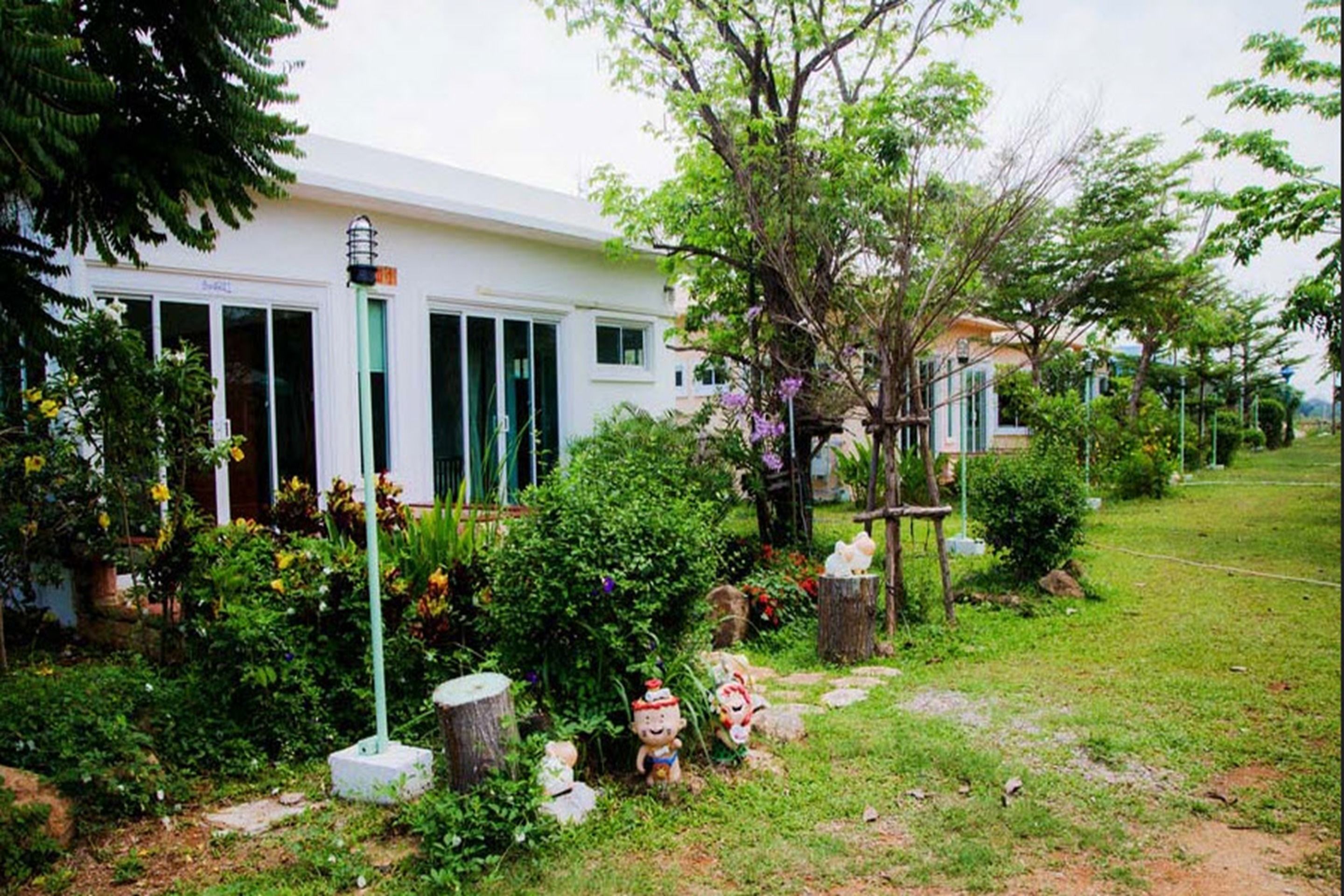A white building with a garden in front.
