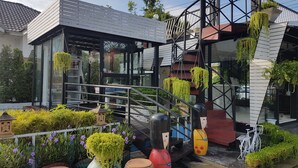 Een modern gebouw met een glazen gevel, een terras en hangende plantenbakken.