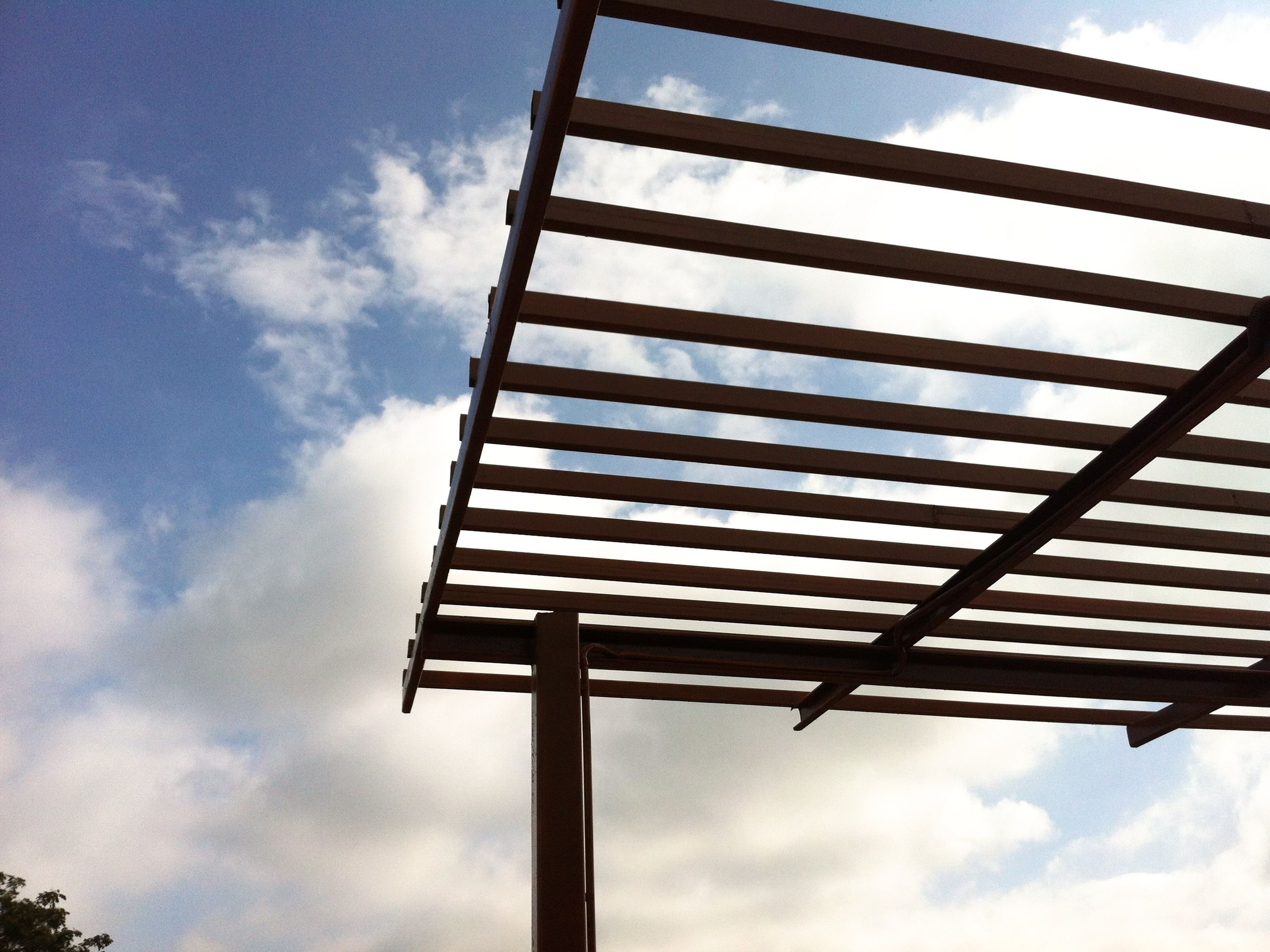 Une structure de pergola en métal se dressant sur fond de ciel nuageux.