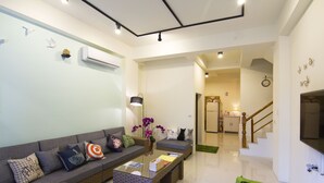 A modern living room with a sofa, coffee table, and a green chair. There is a staircase leading to another room. - Tesla Charging Kimura Elevator B&B (Luodong)
