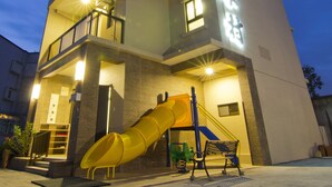 A multi-story building with a children's play area, including a slide and benches. - Tesla Charging Kimura Elevator B&B (Luodong)