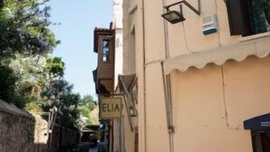 Una calle estrecha flanqueada por edificios, un letrero que dice "ELIA" y un farol.
