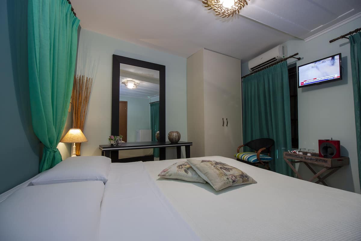 Habitación de hotel con una cama, un escritorio con lámpara, un televisor y una pequeña mesa con altavoz.