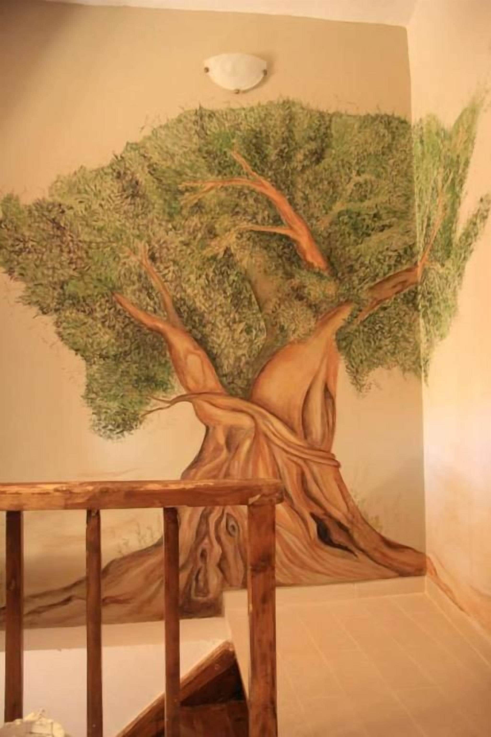 A wall mural of a tree with a wooden railing in the foreground.