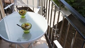 Una mesa redonda de vidrio con dos cestas de fruta en un balcón.