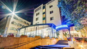 L’entrée d’un hôtel, dotée d’un auvent en verre, avec des marches menant à l’intérieur, et une enseigne indiquant « WAL PLAZA HOTEL ».