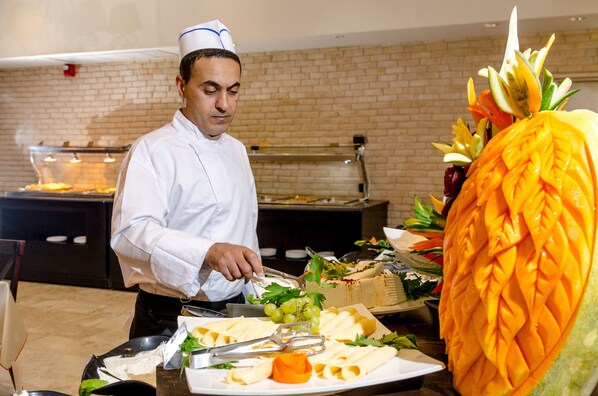 Ein Buffet mit Koch, der Speisen zubereitet, einer großen, geschnitzten Ananas als Mittelpunkt und verschiedenen angebotenen Gerichten.
