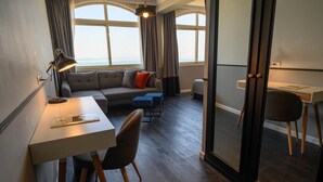 Une chambre d’hôtel moderne, dotée d’un bureau, d’un canapé et offrant une vue sur la mer.