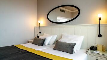 Une chambre d’hôtel avec un lit, une table de chevet avec une lampe, un miroir et un téléphone.