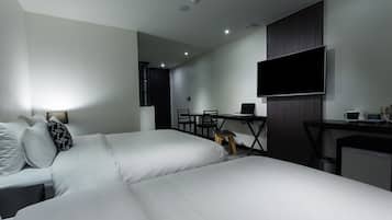 Una habitación de hotel moderna con dos camas, un escritorio, una silla, un televisor y una kitchenette pequeña.