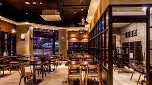 A modern restaurant with wooden furniture, large windows, and a view of the city at night. - Hotel Sienna (Paju)