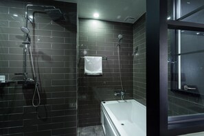 A modern bathroom with a bathtub, a shower with a handheld showerhead, and a towel hanging on a rack.