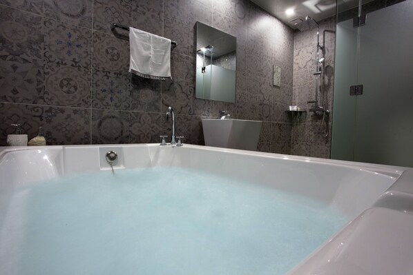 Un baño moderno con una bañera grande, un lavabo y una ducha.