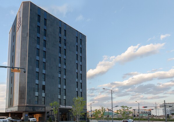 A tall hotel building with a modern design, featuring multiple floors and a prominent entrance.