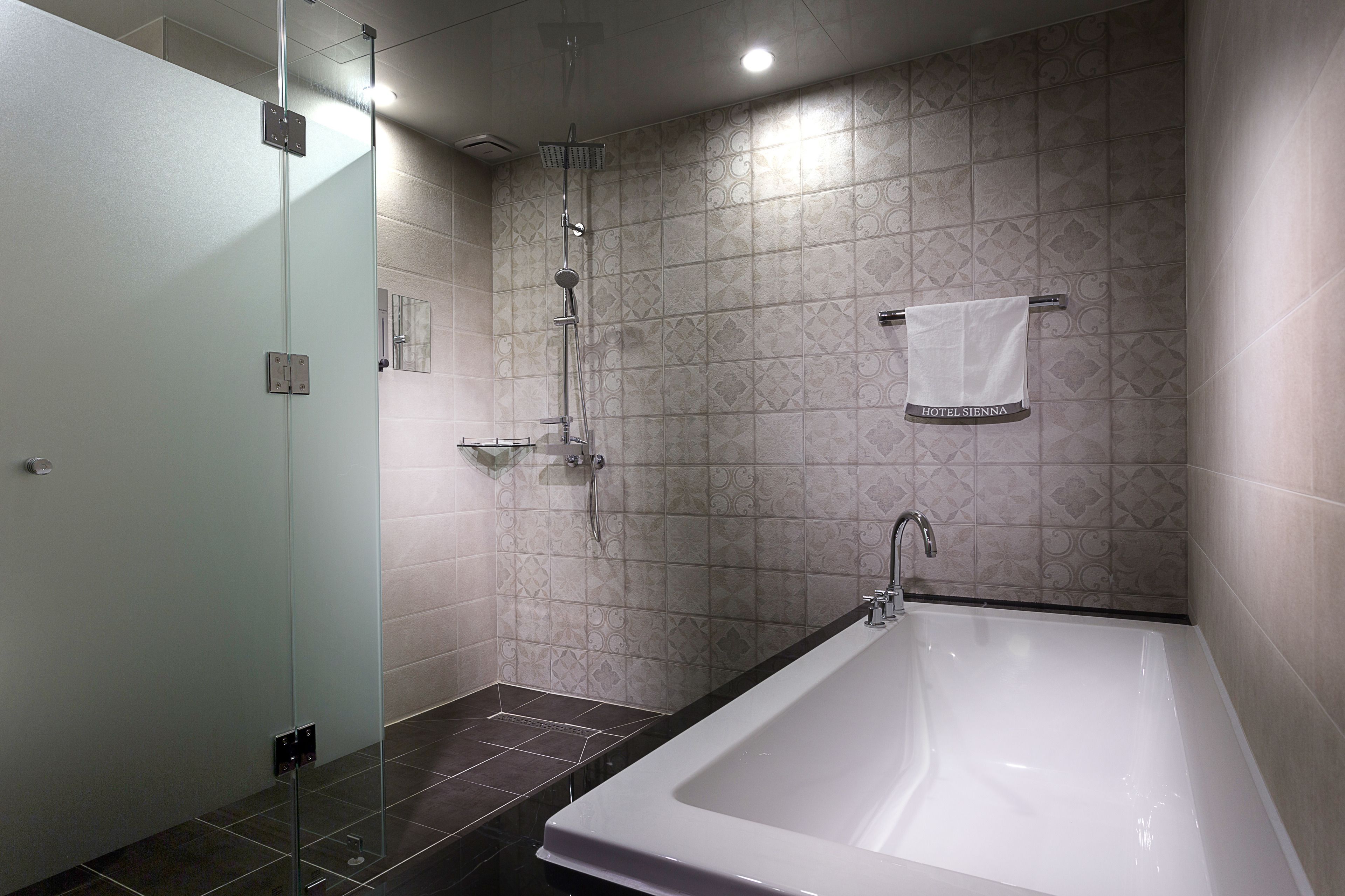 A modern bathroom with a large bathtub, a glass shower enclosure, and patterned tiles.