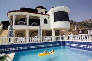Una piscina al aire libre, sombrillas, sillones reclinables de piscina