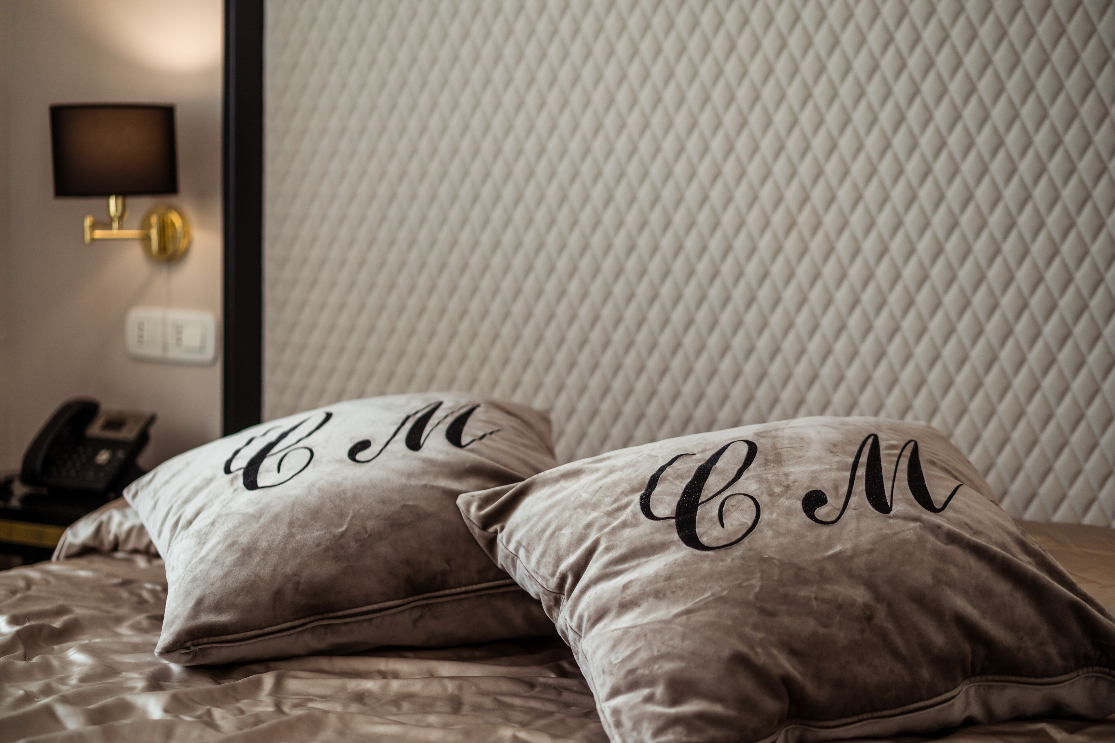 A bed with two pillows, each with a monogrammed design.