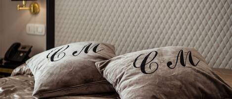 A bed with two pillows, each with a monogrammed design.