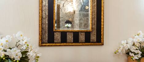 A black leather sofa with gold and black striped frames, white flowers, and a green exit sign on the wall.