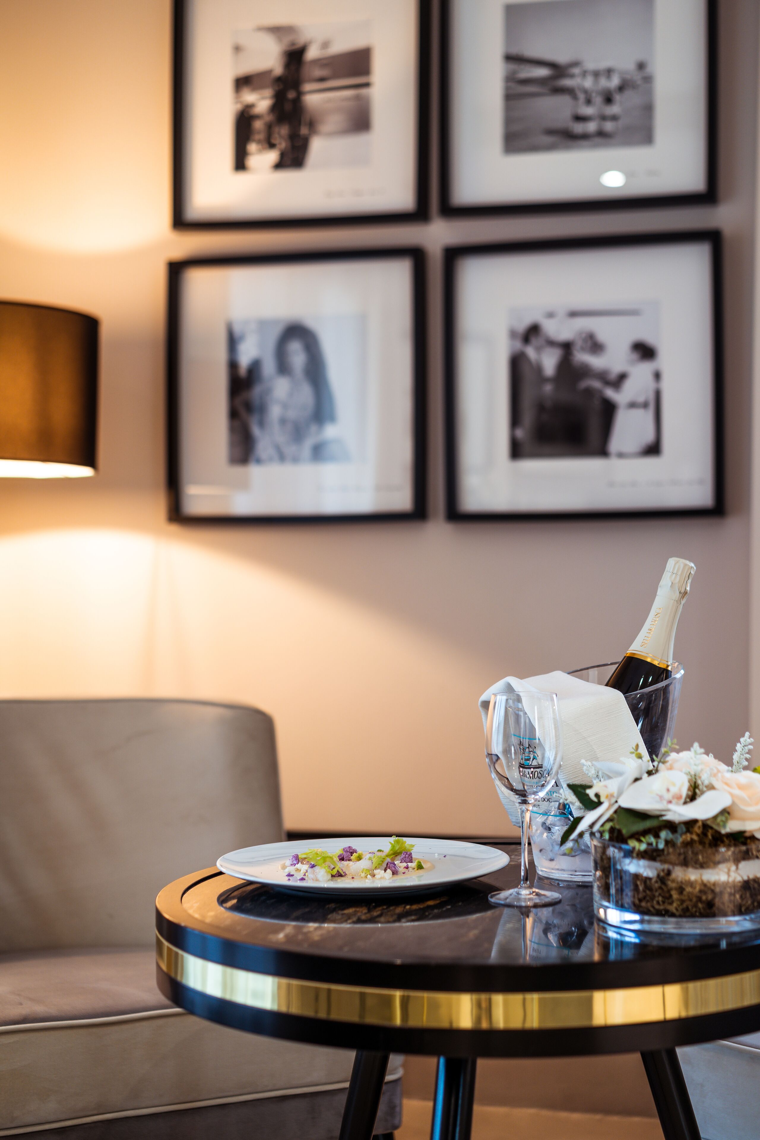 A round table with a bottle of champagne, a glass, and a plate of food.