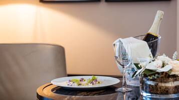 A round table with a bottle of champagne, a glass, and a plate of food.