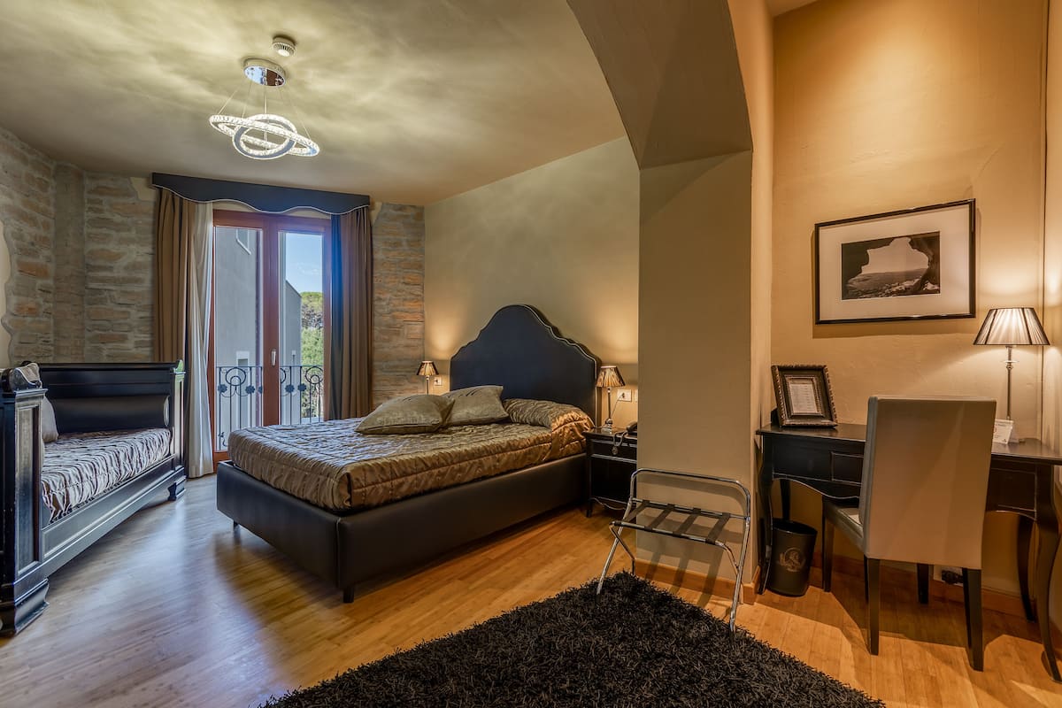 A bedroom with a bed, bedside tables, a desk, and a chair.