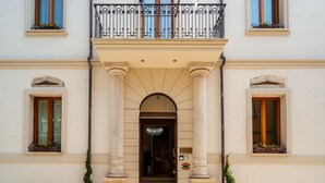 A building with a central entrance flanked by columns, a balcony with wrought iron railings, and flower boxes on the windows. - La Locanda del Conte Mameli (Olbia)