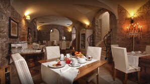 A dining area with stone walls, a chandelier, and tables set for a meal. - La Locanda del Conte Mameli (Olbia)