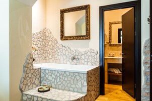 A bathroom with a stone wall, a sink, and a mirror.