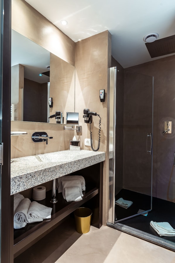 A modern bathroom with a granite countertop, a mirror, a hairdryer, and a shower area. - La Locanda del Conte Mameli (Olbia)
