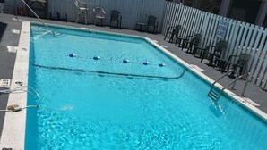 A rectangular swimming pool with clear blue water, marked depth lines, and a pool ladder on one side.