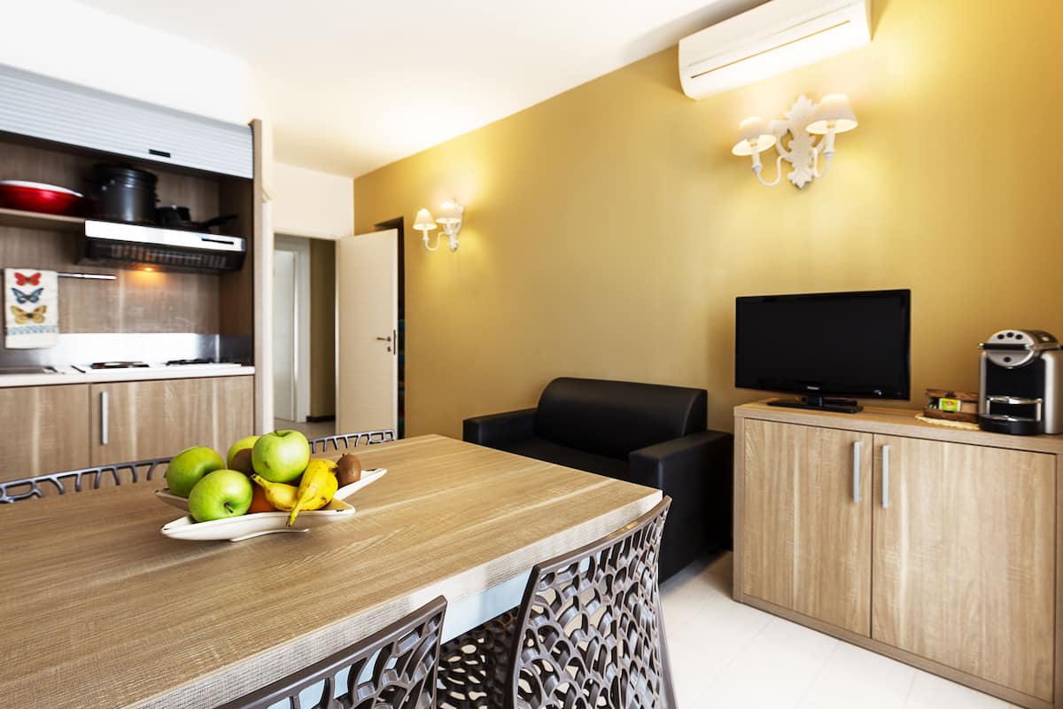 A modern kitchen with a dining table, a TV, and a coffee machine.