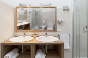 A bathroom with two sinks, a large mirror, and a glass-enclosed shower. - Le Residenze del Centro (Olbia)