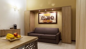 A modern living room with a sofa, a dining table with fruit, and a coffee machine. - Le Residenze del Centro (Olbia)