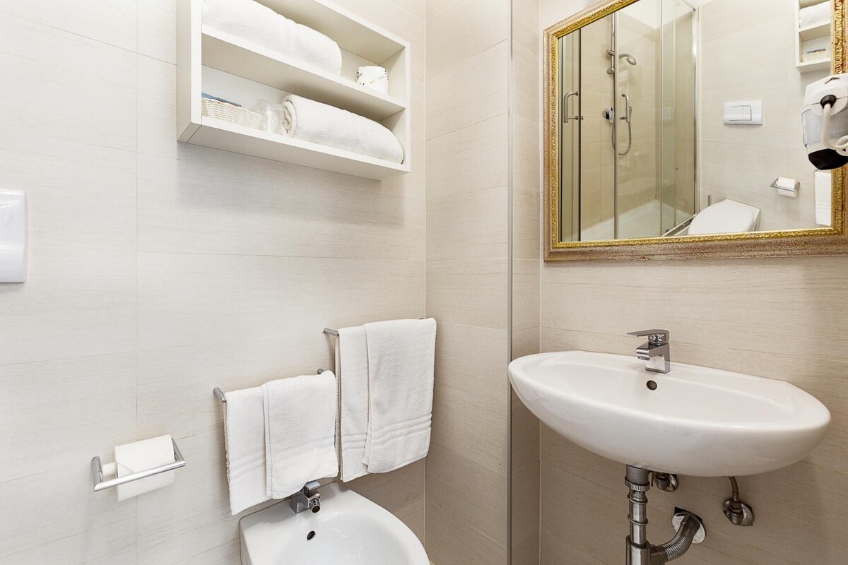 A bathroom with a white sink, a mirror with a gold frame, and a towel rack.