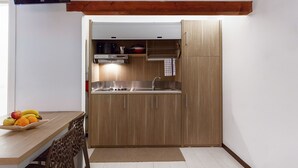 A compact kitchen with a built-in stove, sink, and wooden cabinets. - Le Residenze del Centro (Olbia)