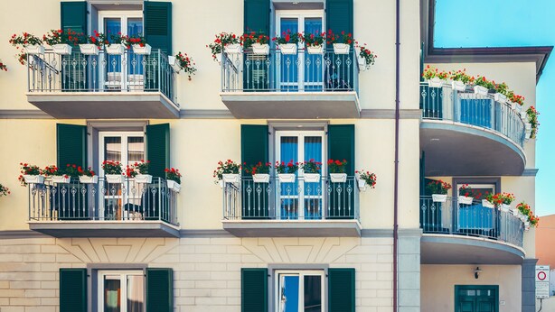 A multi-story building with balconies, each with flower boxes and green shutters. - Le Residenze del Centro (Olbia)
