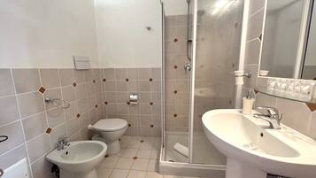 Un baño con ducha, bidé, inodoro y lavabo.