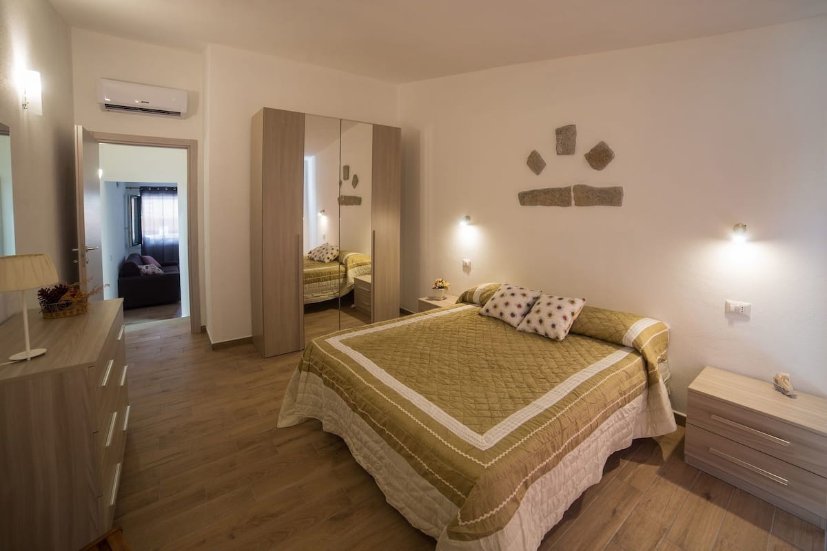 A bedroom with a large bed, a dresser, a mirror, and a nightstand.
