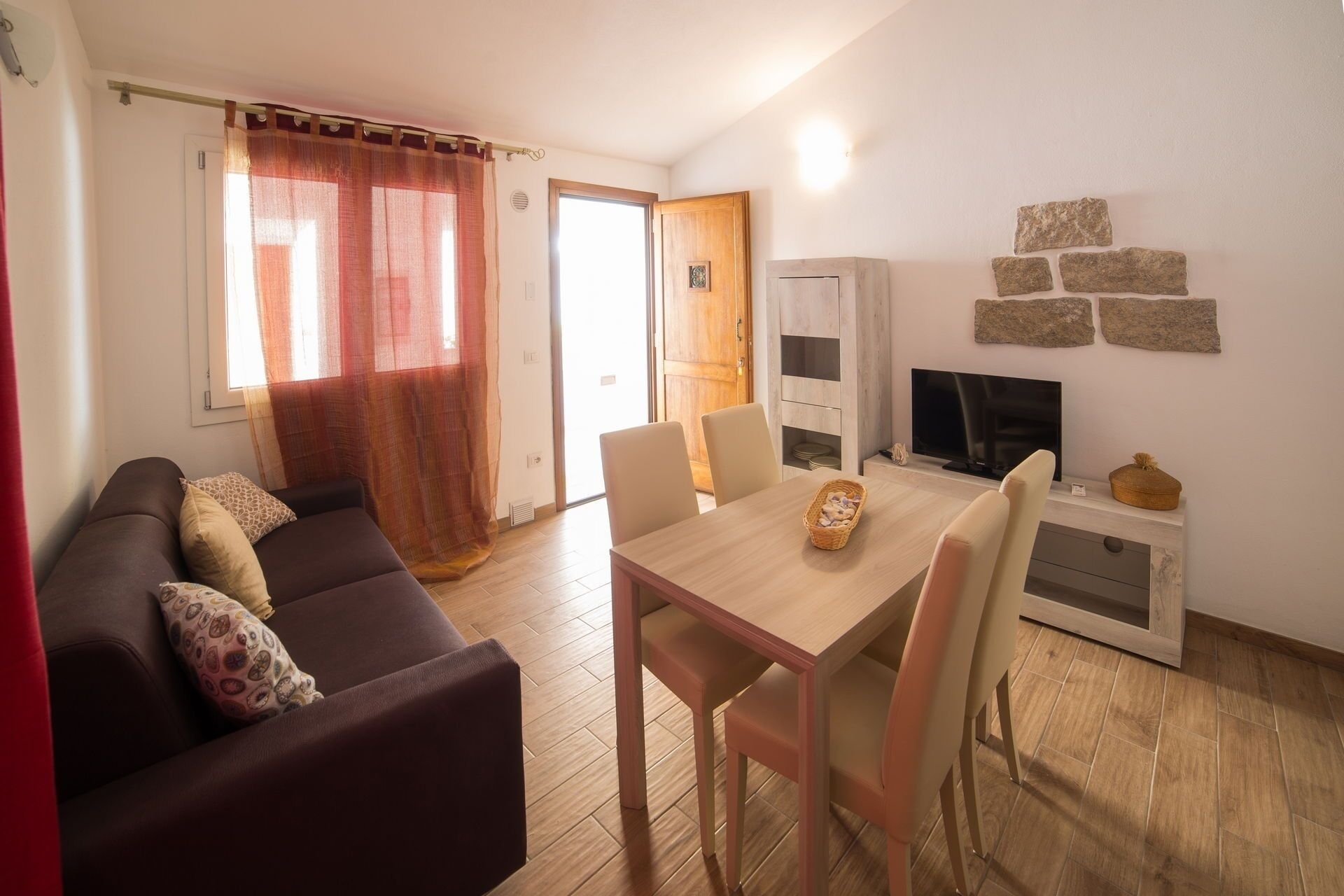Ein Wohnzimmer mit einer Couch, einem Esstisch, Stühlen, einem Fernseher und einem Schrank.