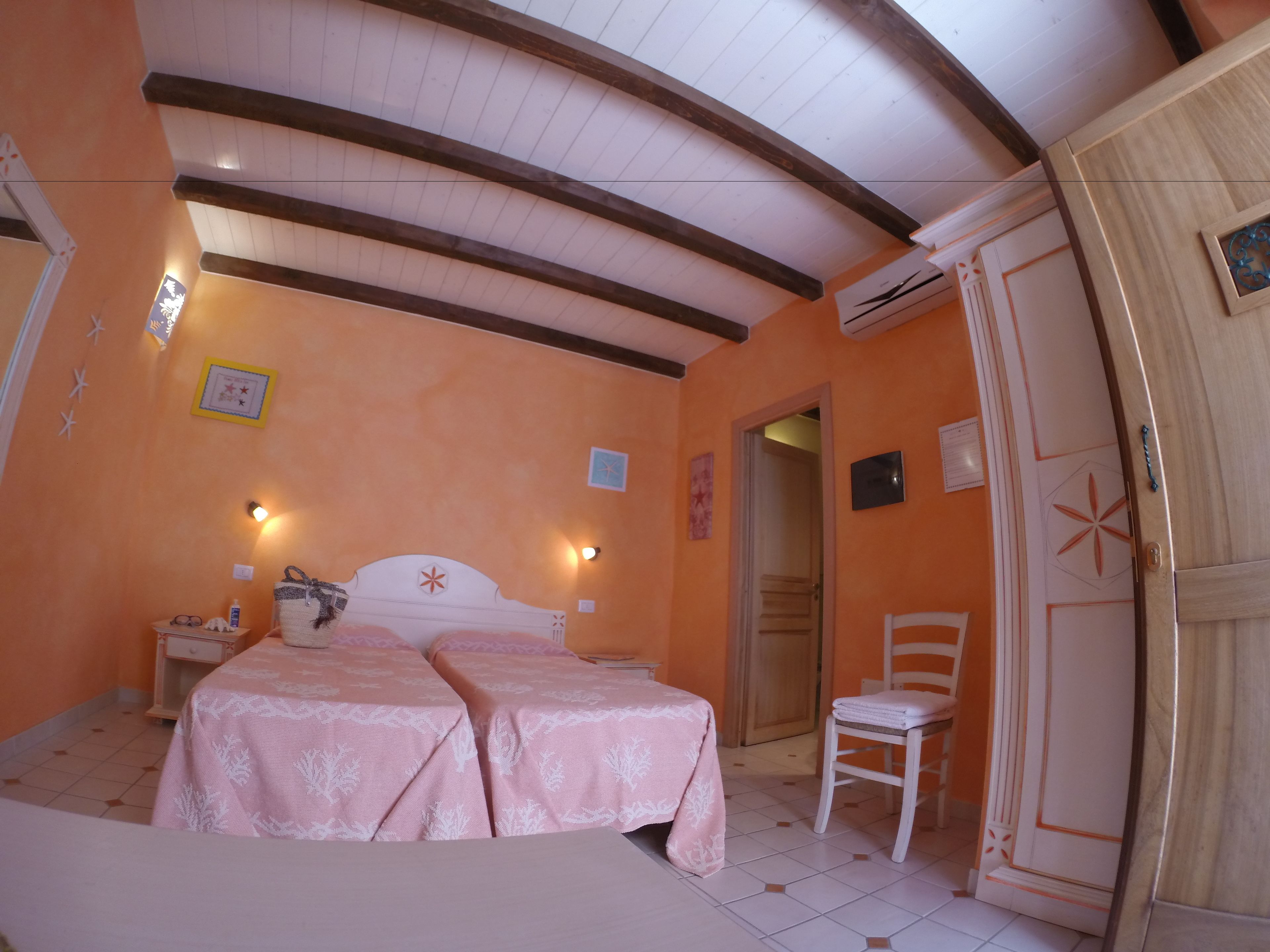 A bedroom with two beds, a chair, and a wardrobe.