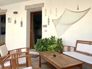 Une table en bois avec un saladier, deux chaises en bois, une plante en pot et un hamac.