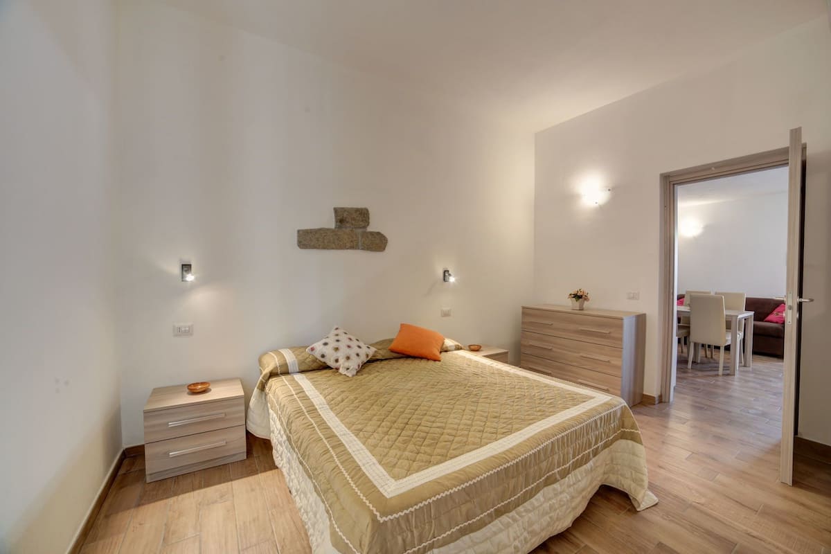 A bedroom with a bed, bedside tables, a dresser, and a wall-mounted light fixture.
