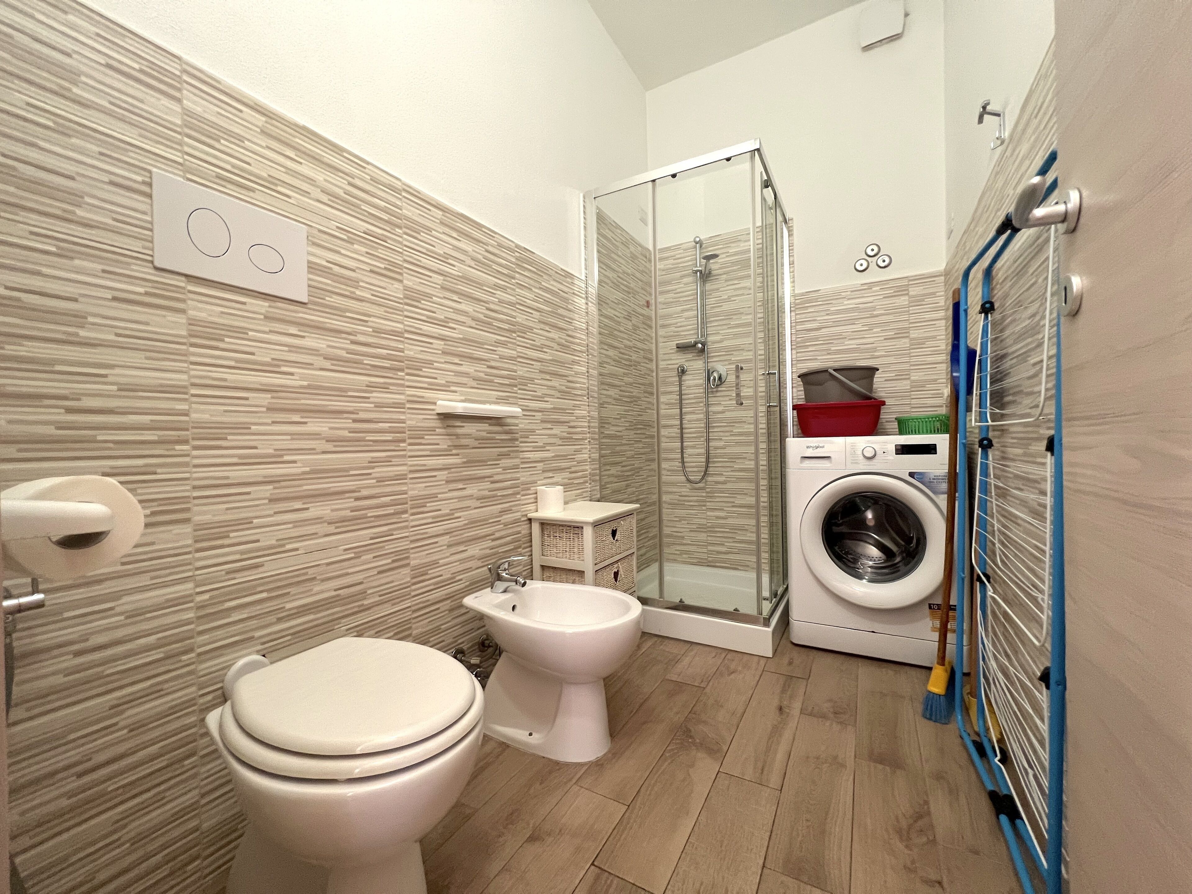 Un baño moderno con inodoro, bidé y ducha con mampara de vidrio.