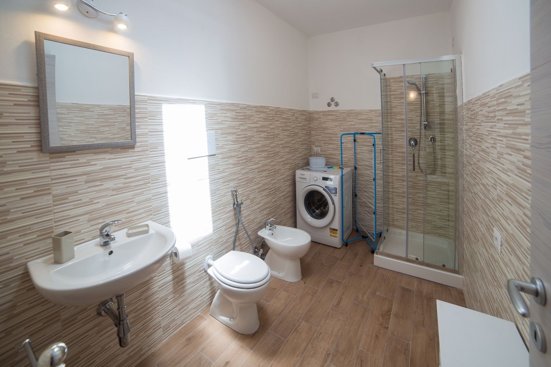 Een moderne badkamer met een wastafel, toilet, wasmachine en douchecabine.